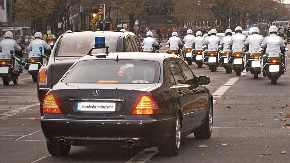 Polizeimotorräder fahren in einer V-Formation gefolgt von sondergeschützen Fahrzeugen des Bundeskriminalamtes (verweist auf: Staatsbesuch)